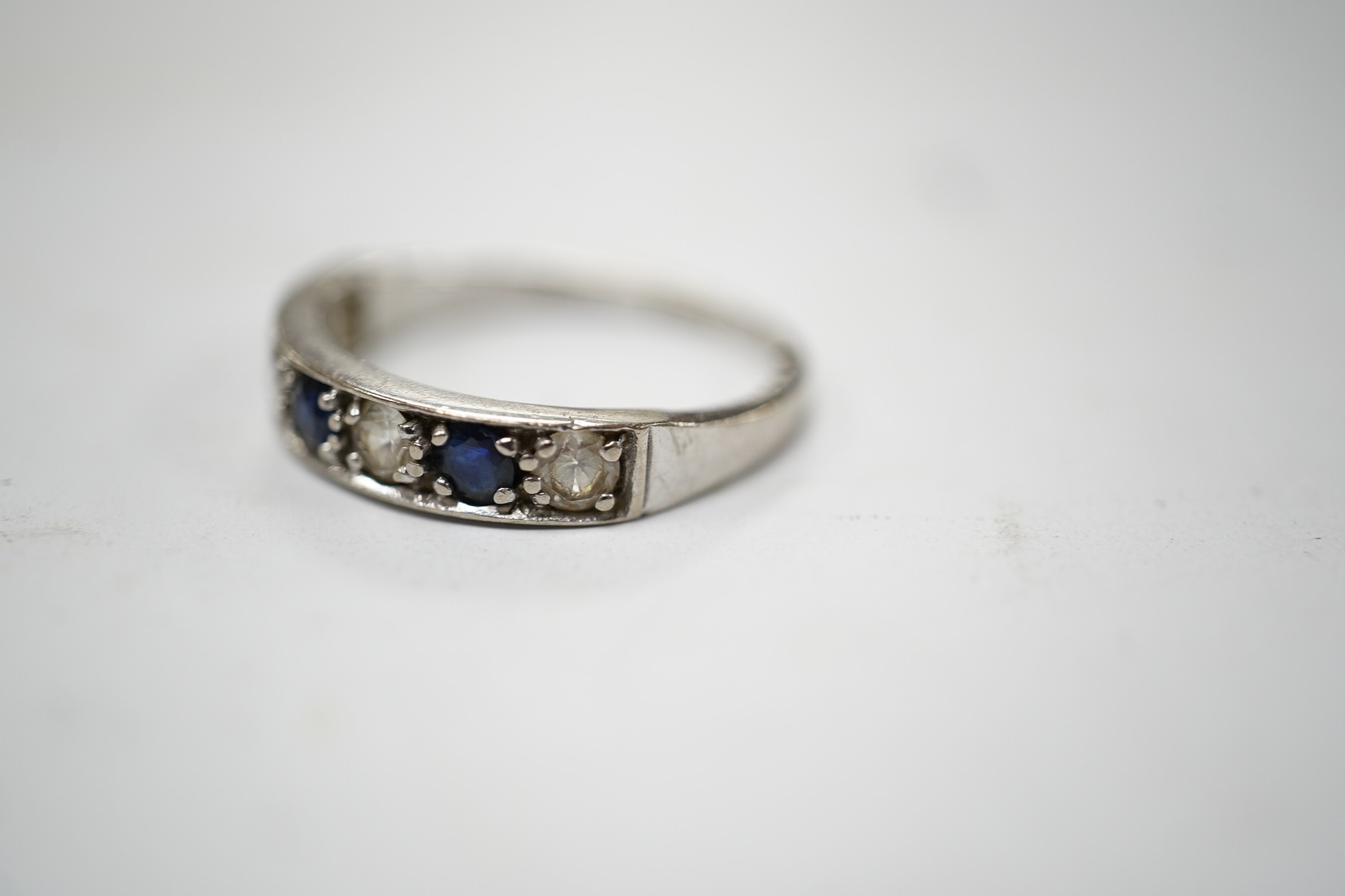 A 1970's 18ct white gold, sapphire and simulated diamond set half hoop ring, size O, gross weight 3.5 grams. Condition - fair